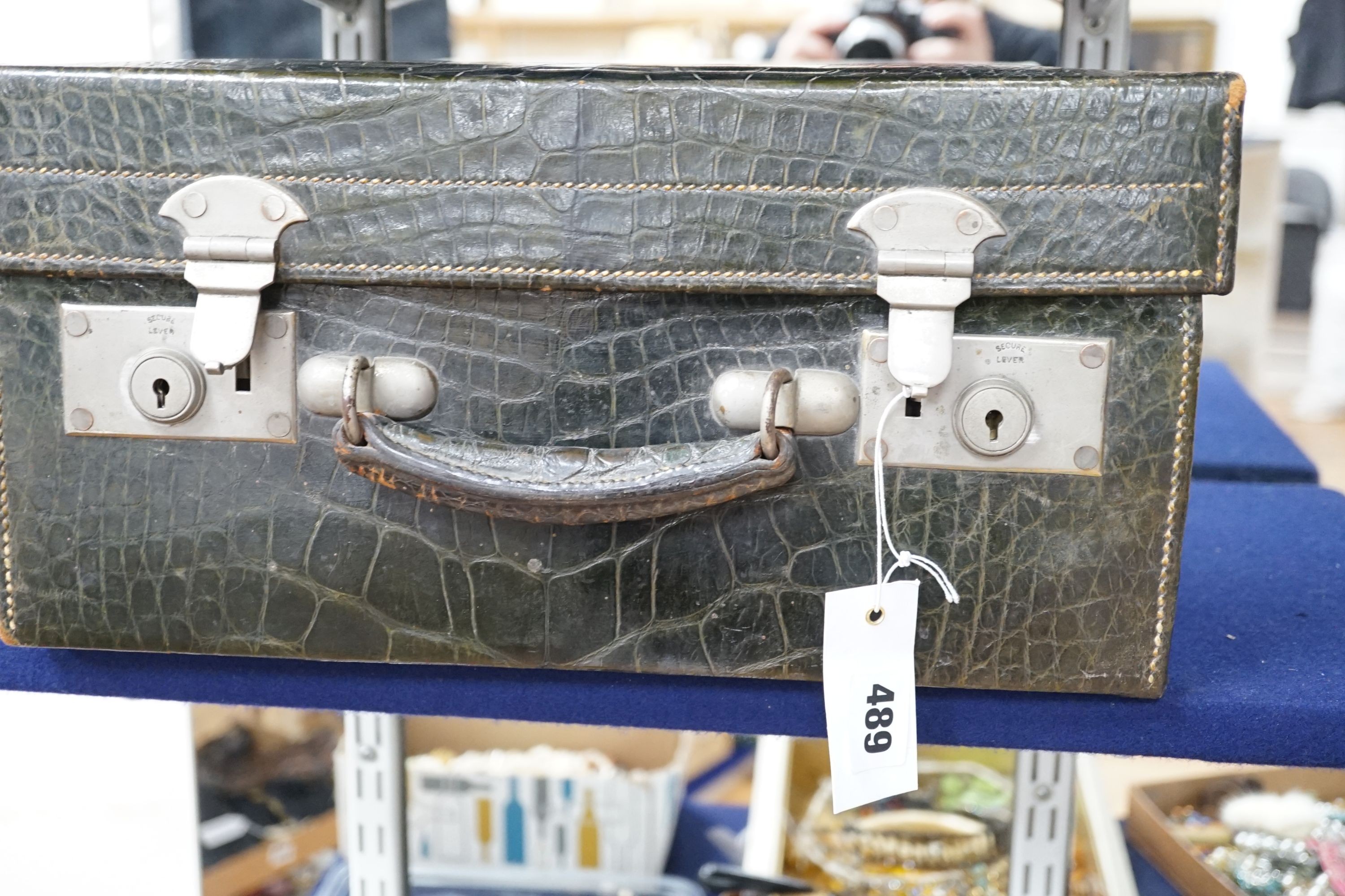 An early 20th century green crocodile toilet case with silver mounted interior, width 39 cms.